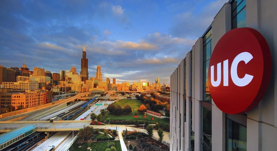 The image shows a view of the Chicago skyline with a UIC building in the foreground and a sunset-lit cityscape under a dramatic sky.